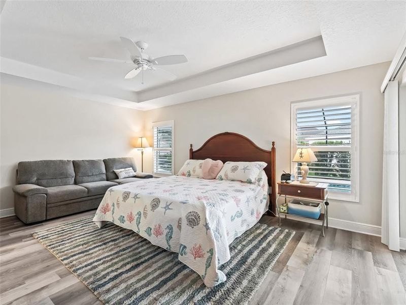 Primary Bedroom with Sliders leading out to the Lanai, Plantation Shutters, And coffered ceiling