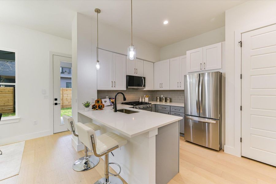 This kitchen is a masterpiece. Featuring crisp white upper cabinetry paired with sophisticated grey lowers, the space is balanced by sleek quartz countertops and a dedicated breakfast bar.