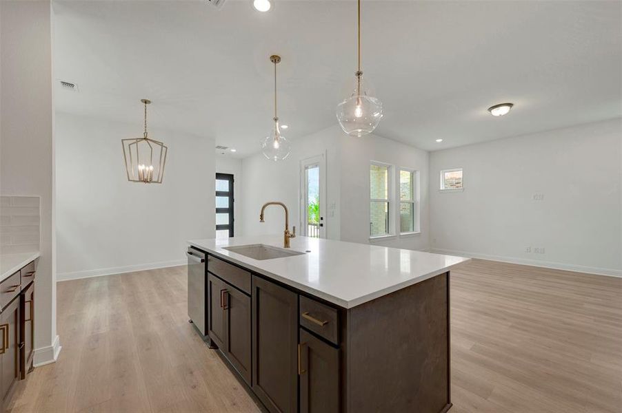 Open concept living space featuring a central island with a white solid surface countertop, integrated sink, and bronze faucet