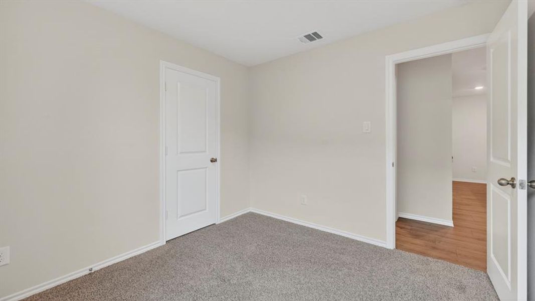 Room featuring gray carpet, light neutral wall paint, white trim, and a white interior door with a dark knob