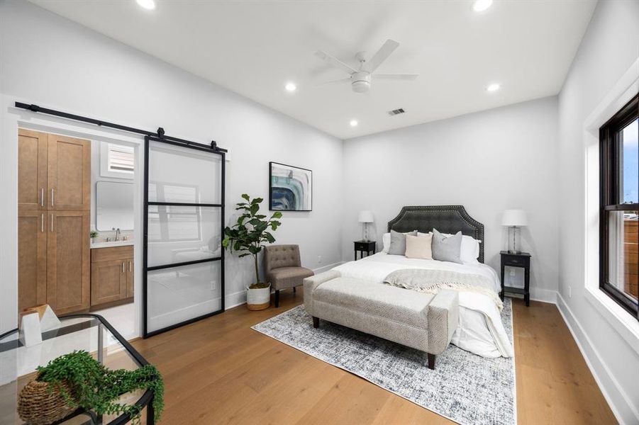 Spacious and elegant primary bedroom featuring a sleek modern sliding door, high ceilings, abundant natural light, and a luxurious en-suite bath.