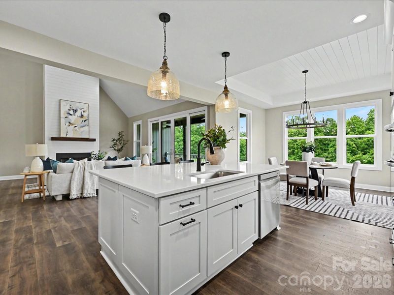 Bright and beautifully designed, this chef’s kitchen features quartz countertops, custom white cabinetry, stainless steel appliances, and a large center island overlooking the open-concept living space.