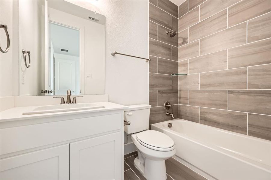 Full bathroom with vanity, tiled shower / bath combo, and toilet