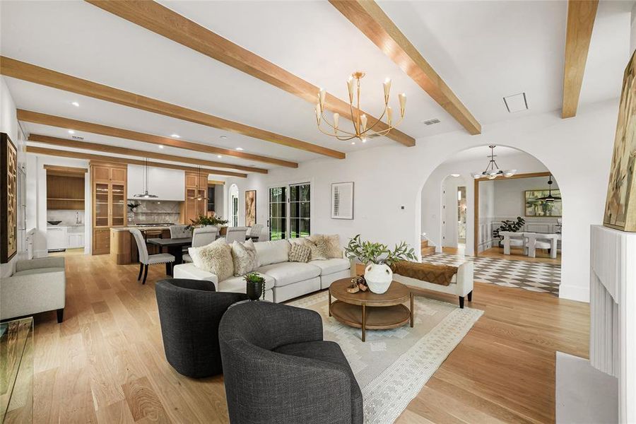 Expansive living area with wood-finish flooring, exposed ceiling beams, and arched doorways