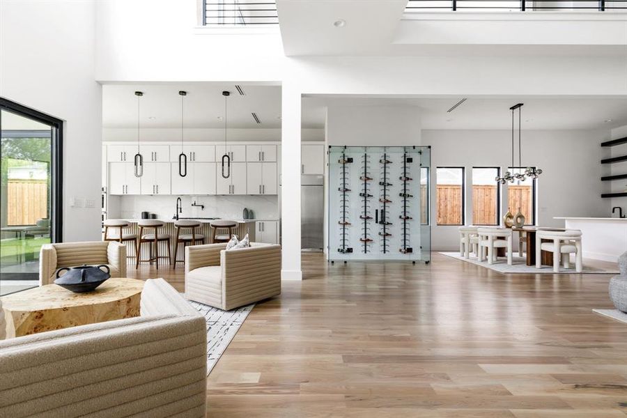 Living room with light wood-type flooring, a chandelier, and a towering ceiling Living room with light wood-type flooring, a chandelier, and a towering ceiling
