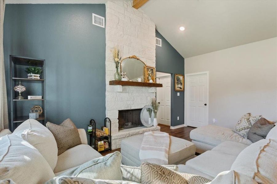 Living area featuring beamed ceiling, a fireplace, wood finished floors, and high vaulted ceiling
