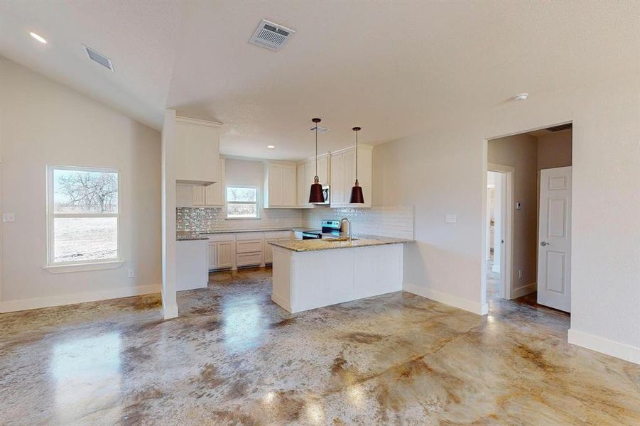 Kitchen with decorative light fixtures, tasteful backsplash, sink, white cabinets, and kitchen peninsula