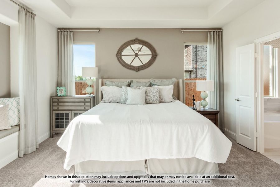 Bedroom with king bed, oval wall mirror, two windows with curtains, and carpet flooring