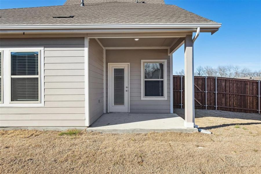 Covered concrete patio with recessed lighting, offering exterior access and two windows with blinds
