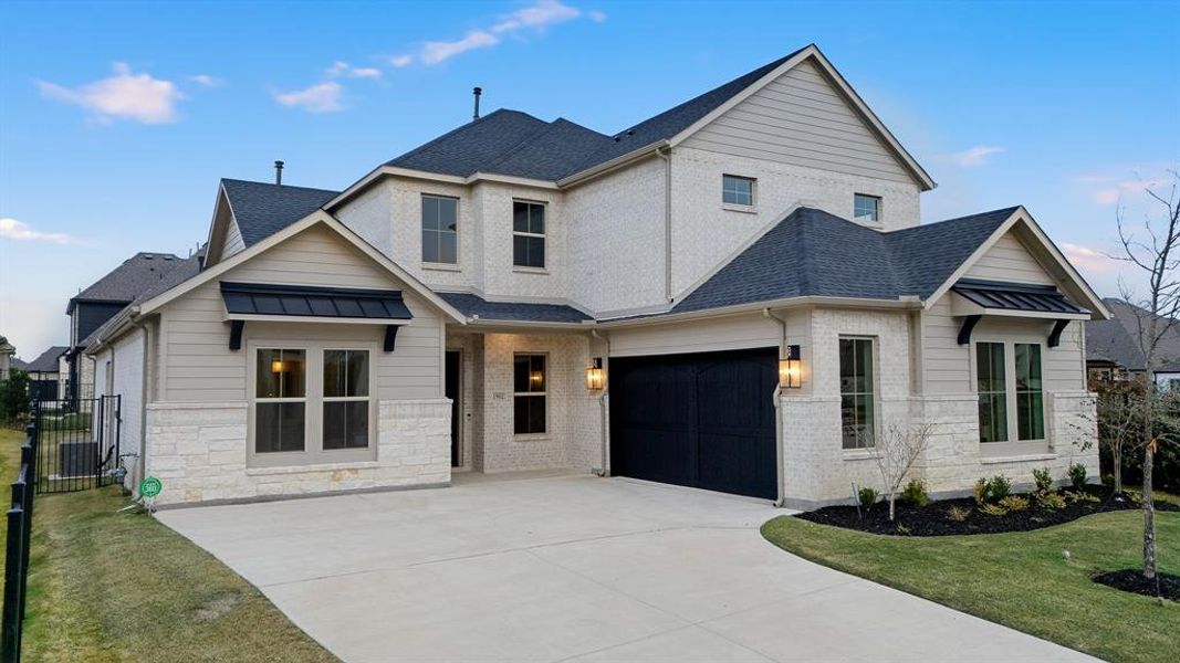 View of front facade with a shingled roof, a garage, driveway, and brick siding