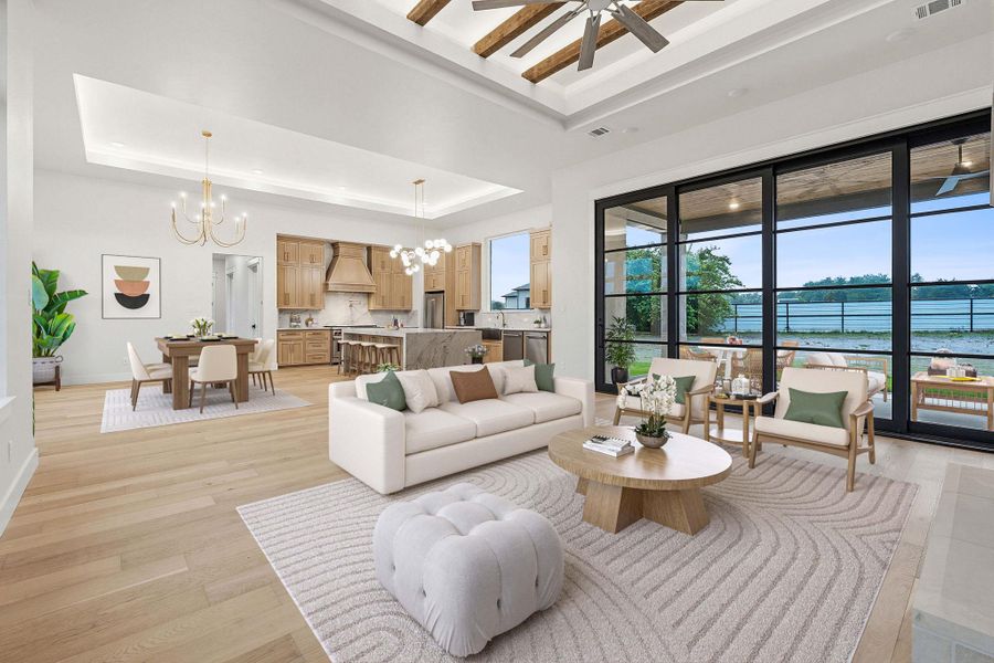 Spacious open-concept living area featuring light wood-finish flooring and a tray ceiling with exposed wooden beams