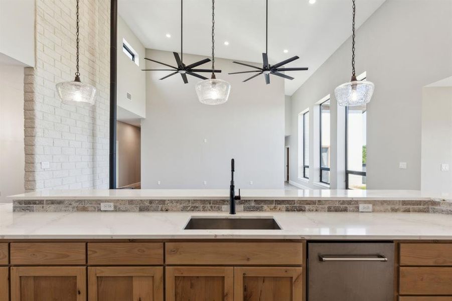 Kitchen featuring plenty of natural light, light stone countertops, high vaulted ceiling, and sink Kitchen featuring plenty of natural light, light stone countertops, high vaulted ceiling, and sink