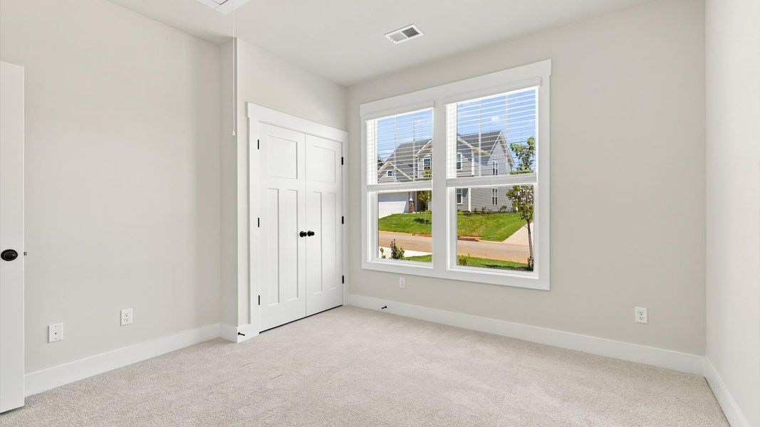 Tasteful bedroom with plush carpet, a walk-in closet, and large windows for abundant natural light by DRB Homes