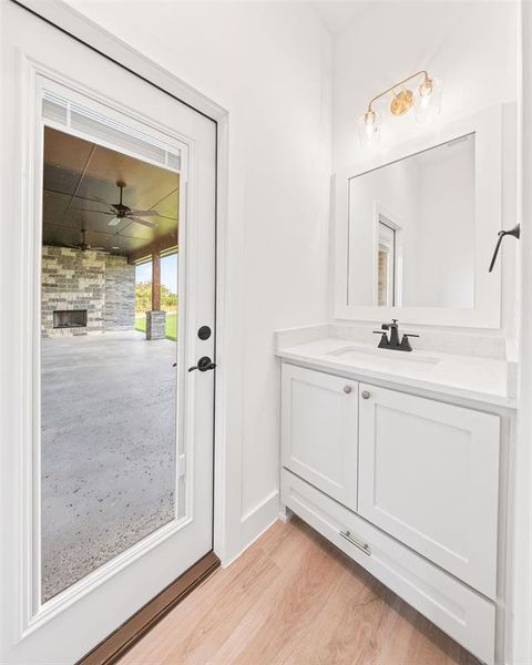 Bathroom featuring a fireplace, vanity, light wood-style floors, and a ceiling fan Bathroom featuring a fireplace, vanity, light wood-style floors, and a ceiling fan