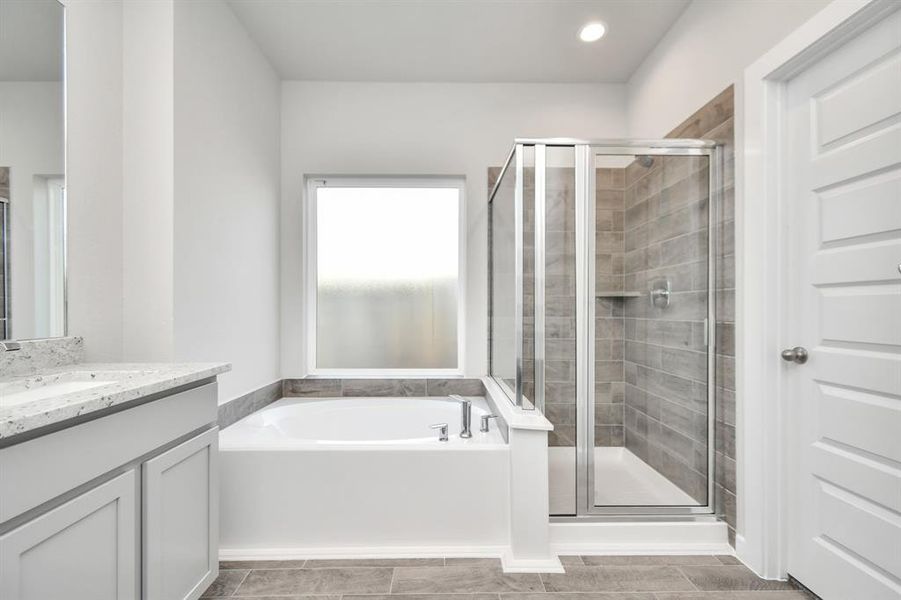 The primary en-suite has a soaking tub to give you that spa experience. The large privacy window allow lots of nature light in the space. Sample photo of completed home with similar floor plan. As-built interior colors and selections may vary.