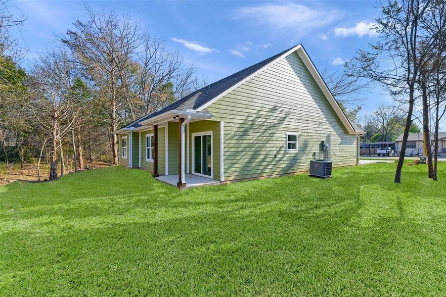 Rear view of property featuring a yard and central AC