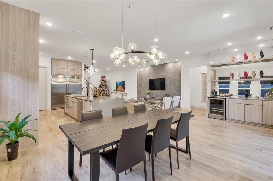 Dining room featuring sink, a notable chandelier, light hardwood / wood-style floors, and wine cooler