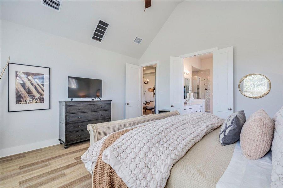 Bedroom with light wood-type flooring, lofted ceiling, a ceiling fan, and connected bathroom Bedroom with light wood-type flooring, lofted ceiling, a ceiling fan, and connected bathroom