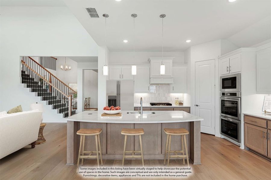 Open kitchen with large island, three bar stools, white cabinets, stainless appliances, and hardwood floors
