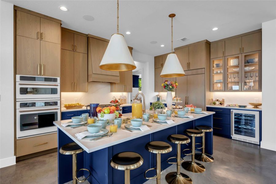 Gourmet kitchen featuring a large central island with seating, a built-in double oven, wood-finish cabinetry, a beverage refrigerator.