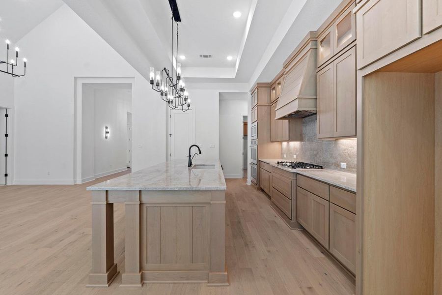 Kitchen featuring a chandelier, light stone counters, backsplash, a center island with sink, and recessed lighting Kitchen featuring a chandelier, light stone counters, backsplash, a center island with sink, and recessed lighting