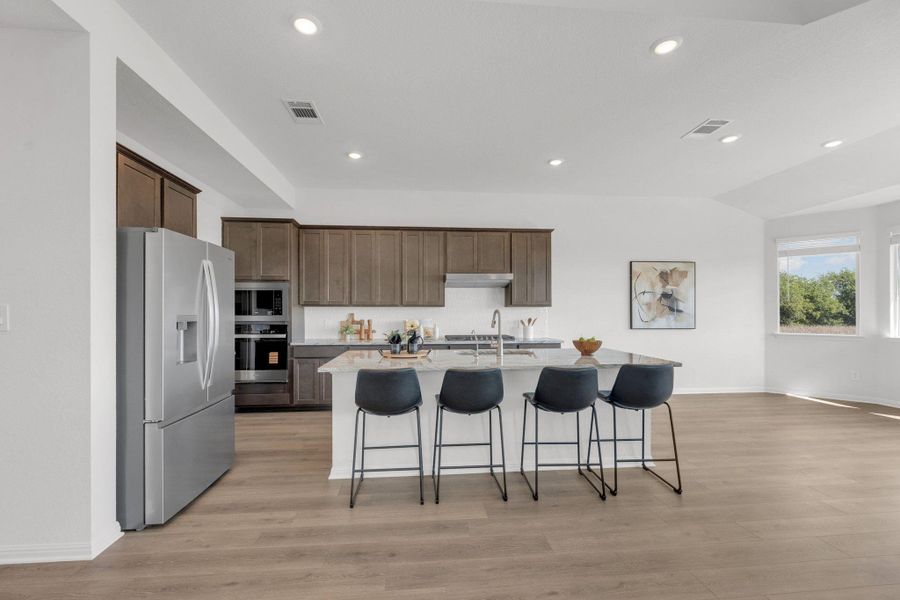 Kitchen with a kitchen bar, stainless steel appliances, an island with sink, recessed lighting, and light stone countertops Kitchen with a kitchen bar, stainless steel appliances, an island with sink, recessed lighting, and light stone countertops