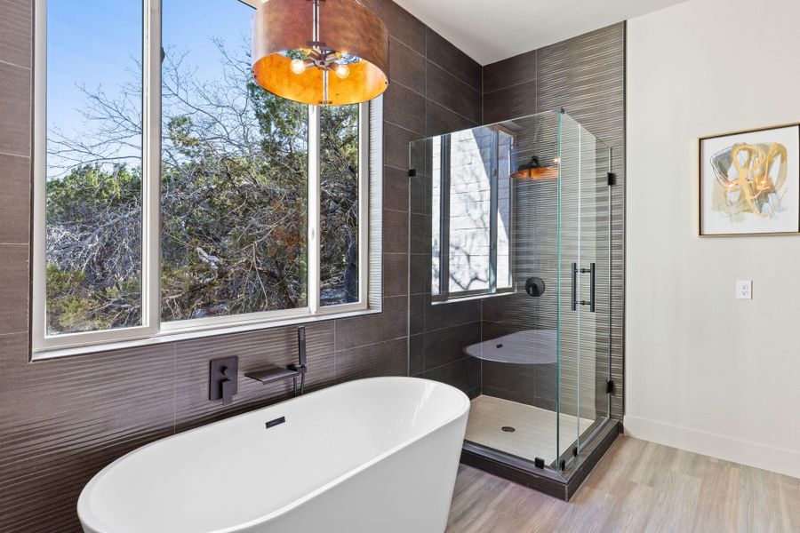 Full bath featuring a wealth of natural light, a soaking tub, a stall shower, and baseboards