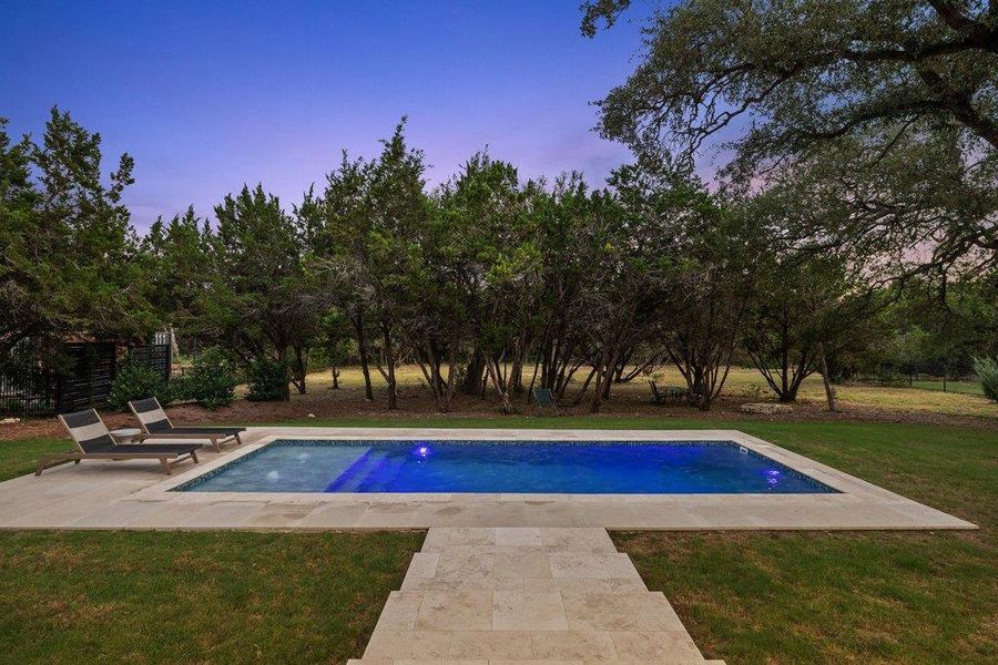 An inviting in-ground pool awaits in a serene setting, flanked by lush trees and manicured lawn. An inviting in-ground pool awaits in a serene setting, flanked by lush trees and manicured lawn.