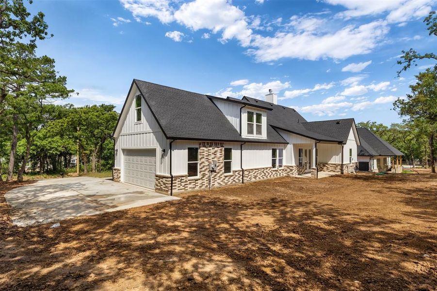 The property features a white exterior with stone accents, a dark roof, and a garage