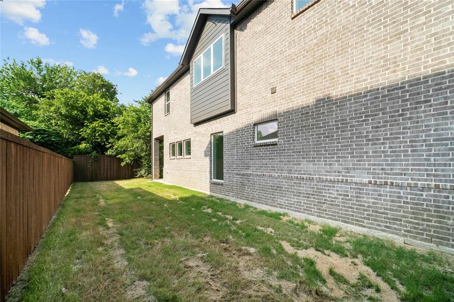 View of property exterior with brick siding and a fenced backyard