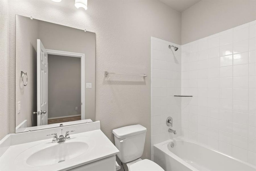 The secondary bath features tile flooring, white cabinetry and light countertops and a shower/tub combo. Perfect for accommodating any visiting family and friends.