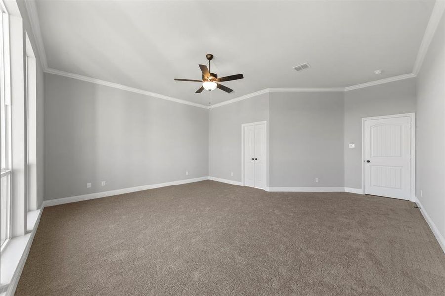 Carpeted empty room featuring ornamental molding and ceiling fan