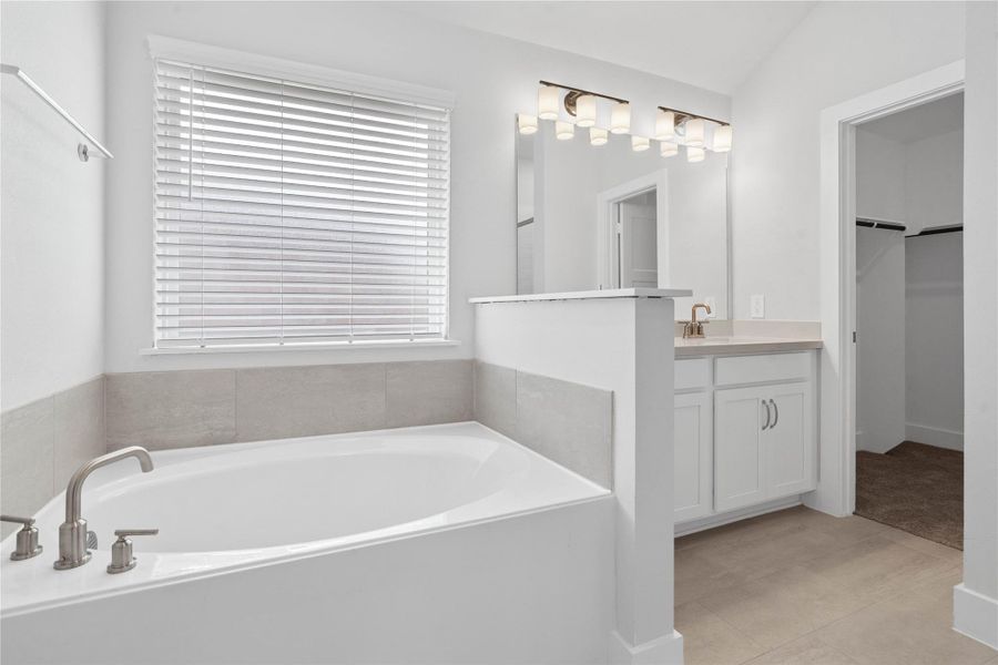 Indulge in the primary bath's deep, built-in soaking tub with elegant fixtures and a sleek tile surround for a true spa-like retreat.