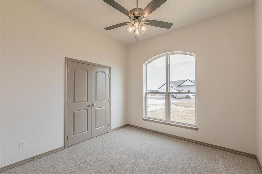 Unfurnished bedroom featuring light colored carpet, a ceiling fan, and a closet