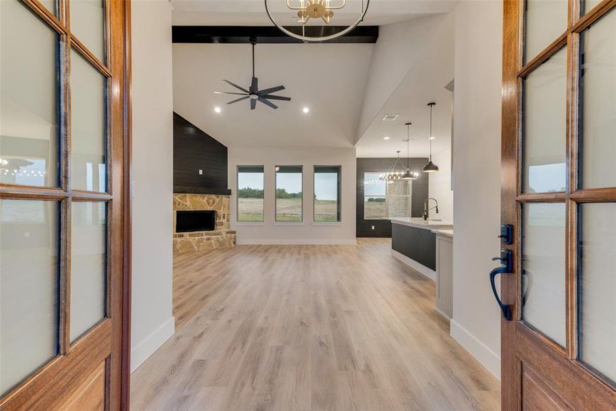 Unfurnished living room featuring a chandelier, a fireplace, a ceiling fan, light wood finished floors, and recessed lighting Unfurnished living room featuring a chandelier, a fireplace, a ceiling fan, light wood finished floors, and recessed lighting