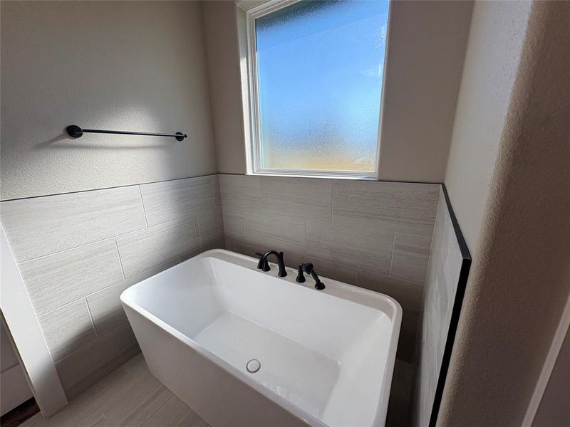 Bathroom with a soaking tub and a textured wall