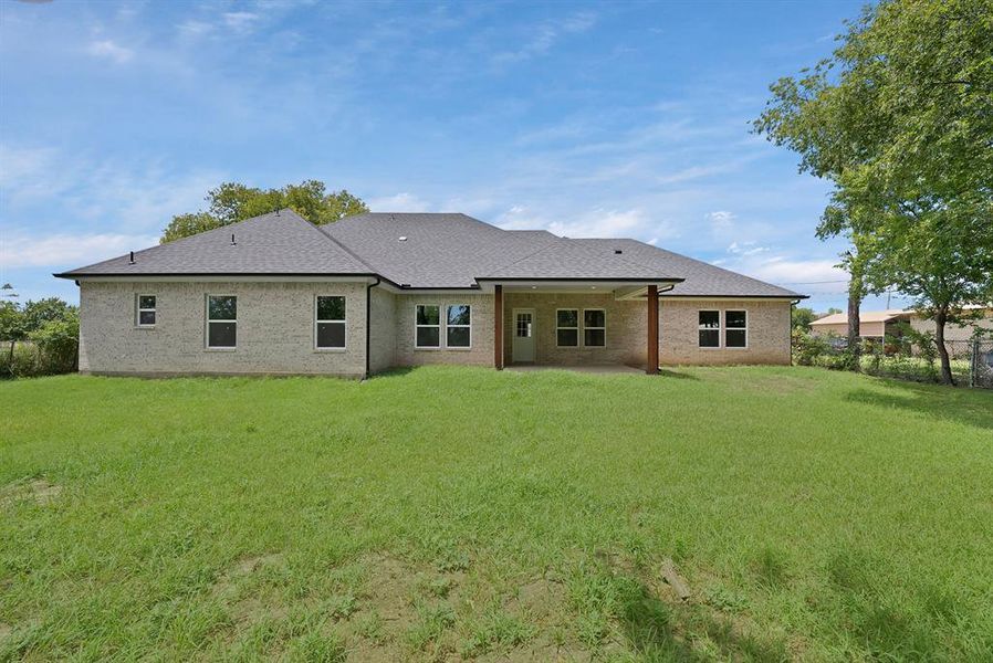 Rear view of property with a patio, a shingled roof, and brick siding