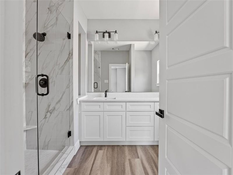 Bathroom featuring a marble finish shower, vanity, and wood finished floors