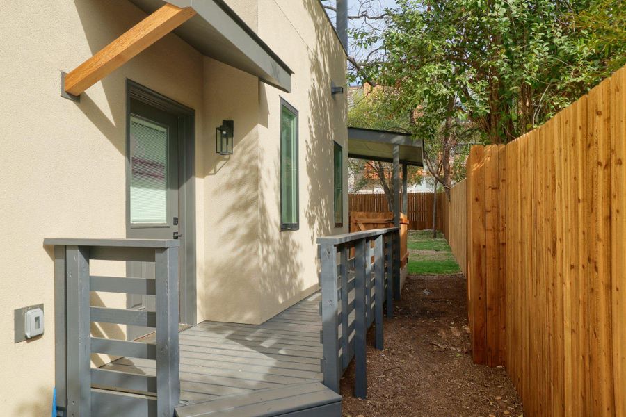 Property entrance with stucco siding and a wooden deck