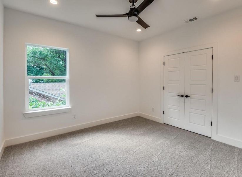 Spare room with light carpet, a healthy amount of sunlight, and ceiling fan