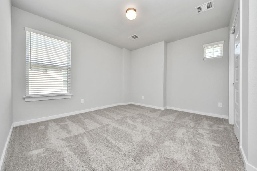 Secondary bedroom features plush carpeting, large windows that let in plenty of natural light, bright paint, and spacious closets. Sample photo of completed home with similar floor plan. Actual colors and selections may vary.