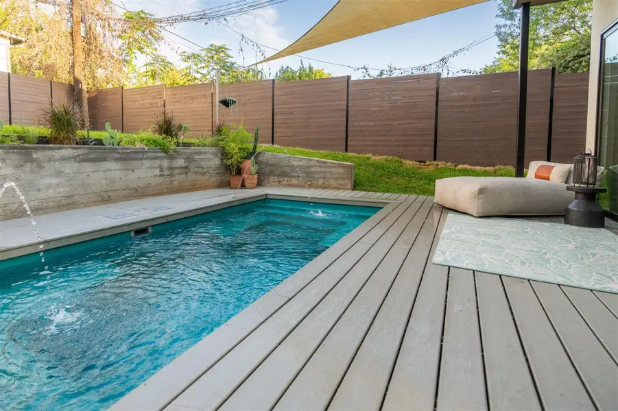 An inviting backyard oasis centers around a custom swimming pool with a modern surrounding deck. An inviting backyard oasis centers around a custom swimming pool with a modern surrounding deck.