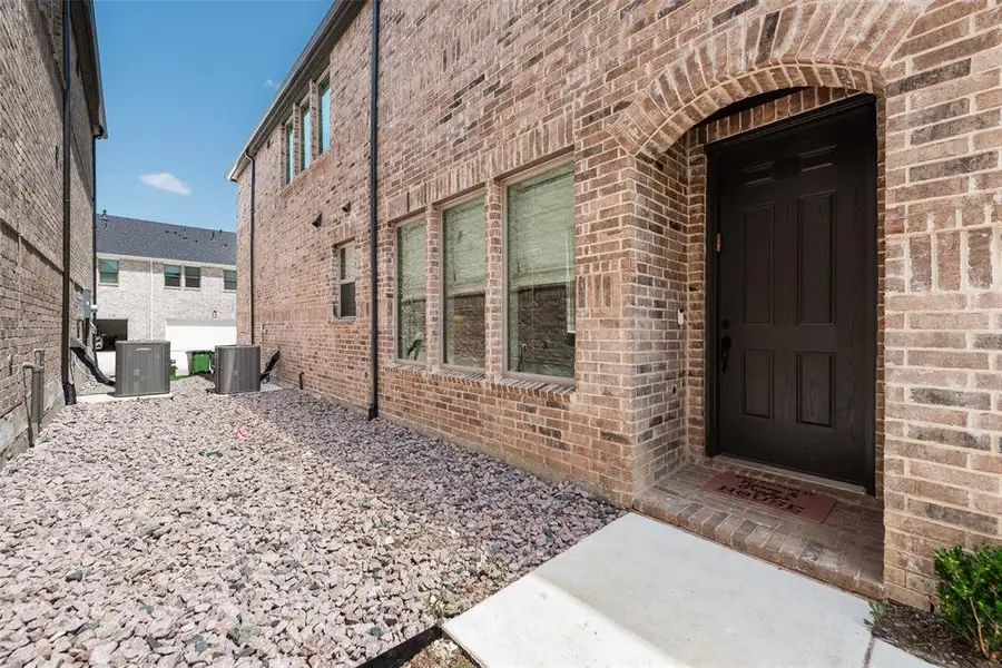 Brick exterior facade featuring a dark paneled entry door with an arched brick surround Brick exterior facade featuring a dark paneled entry door with an arched brick surround
