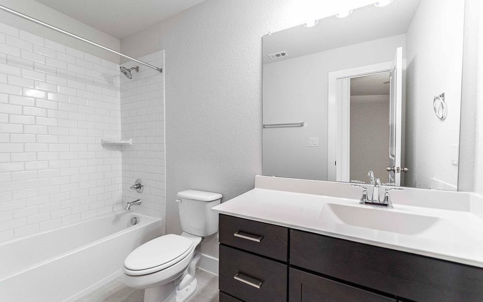 Full bath with bathtub / shower combination, toilet, visible vents, vanity, and baseboards