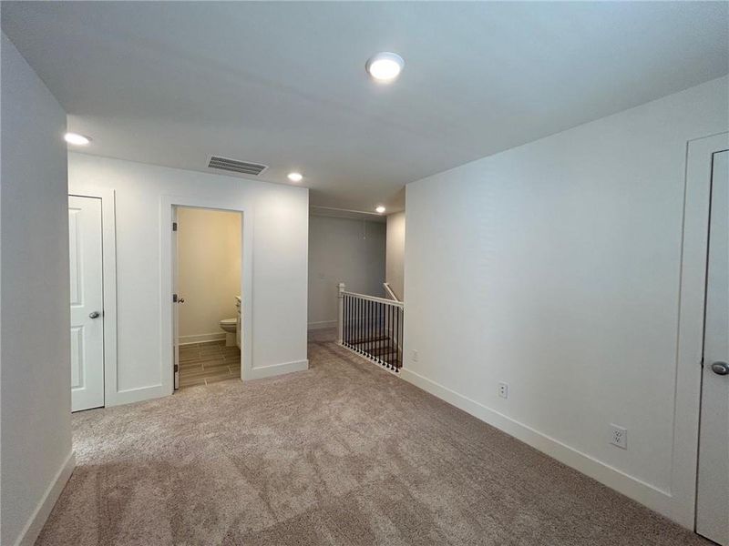 Unfurnished bedroom featuring ensuite bath and light carpet