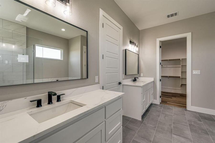 Bathroom featuring a tile shower, tile patterned flooring, and vanity