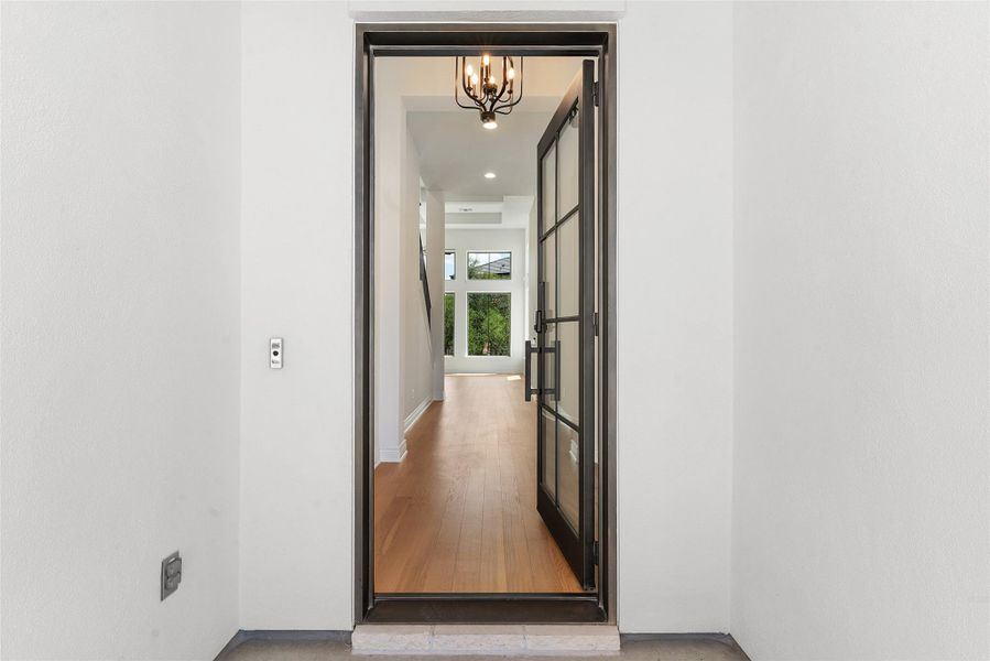 Beyond the striking glass and metal entry, a spacious hall with gleaming wood floors beckons.