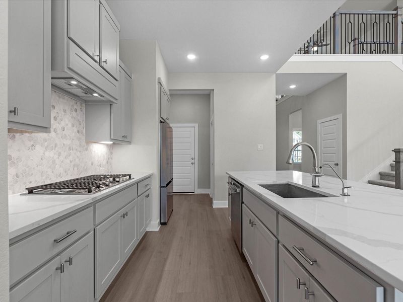 Elegant quartz surfaces, complemented by gray cabinetry & white/gray mix stone backsplash. Gas range cooktop Elegant quartz surfaces, complemented by gray cabinetry & white/gray mix stone backsplash. Gas range cooktop