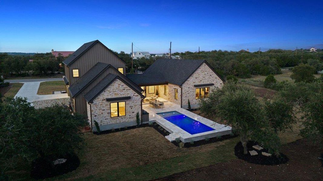 An inviting pool shimmers next to a stone-clad home, perfect for evening gatherings.