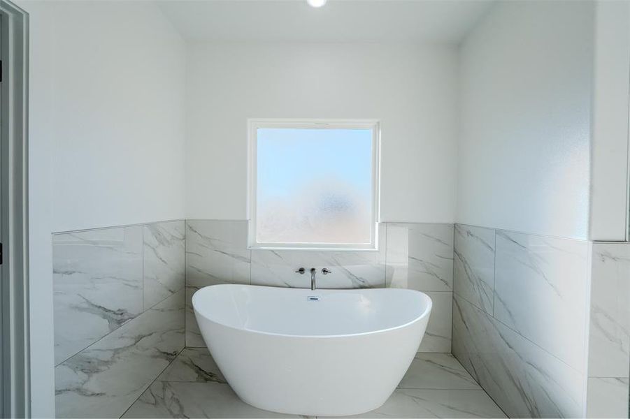 Bathroom with marble finish floors, a freestanding tub, tile walls, a wainscoted wall, and recessed lighting Bathroom with marble finish floors, a freestanding tub, tile walls, a wainscoted wall, and recessed lighting
